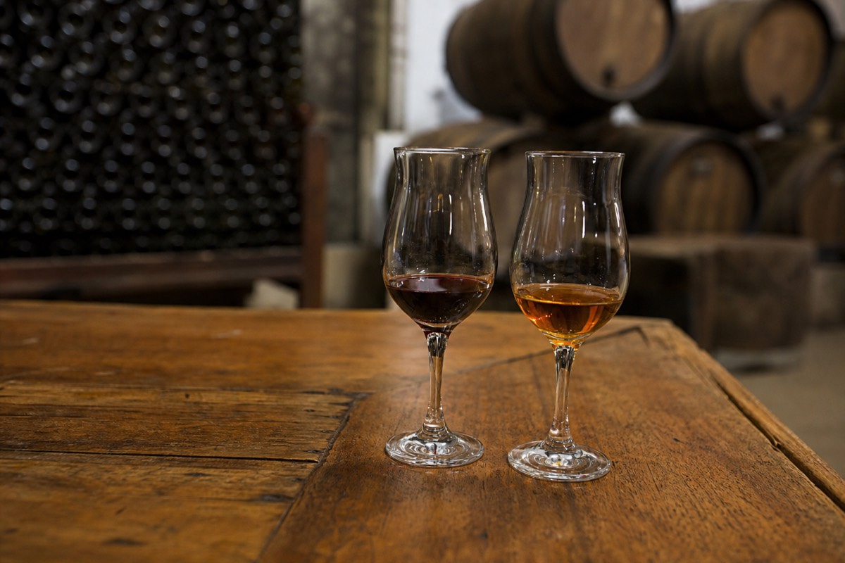 A small tulip glass of tawny Port held up against warm light during a tasting
